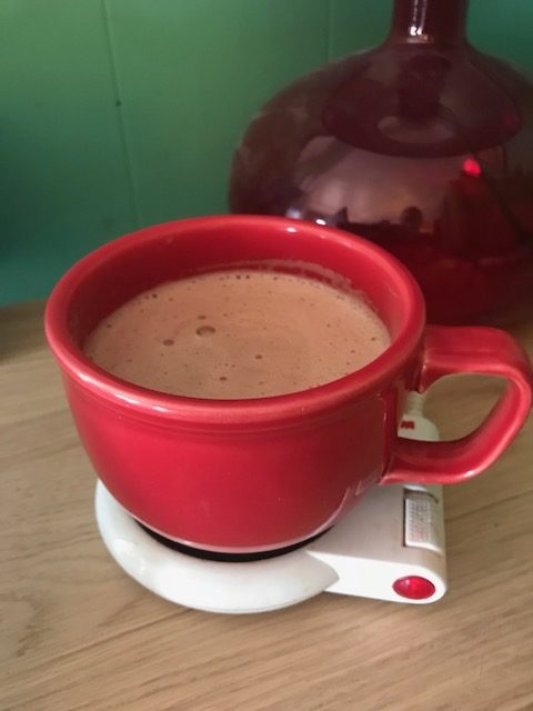 High protein hot chocolate in a red mug on mug warmer